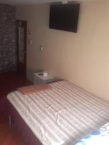 1 dormitorio con 1 cama y TV en la pared en Hostal El Auténtico Diamante, en Quito