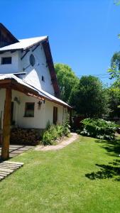 una casa blanca con un patio de hierba delante de ella en El Tranco - Casa "Tu Lugar" en Junín de los Andes