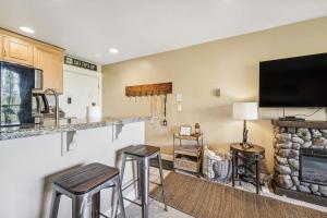 a living room with stools and a flat screen tv at Truckee Studio with Balcony and On-Site Skiing! in Truckee