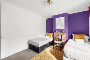 2 Betten in einem Zimmer mit lila Wänden in der Unterkunft BridgeCity Luxurious House in heart of Maidstone in Maidstone