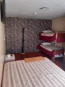 a bedroom with two bunk beds and a brick wall at Hostal El Auténtico Diamante in Quito
