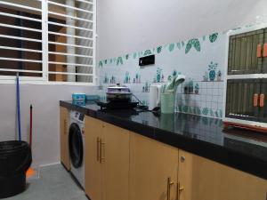 a kitchen with a counter and a washing machine at Double Nine Homestay - Sri Indah Condominium in Sandakan
