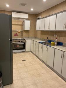 uma cozinha com armários brancos e um frigorífico preto em وناسه مودرن em Riyadh