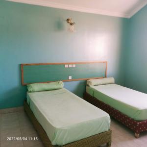 Duas camas num quarto com paredes azuis em HOTEL NAGJIR PLAGE em Laayoune