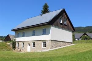 a barn with a metal roof on a grass field at Studia Pod Lysou in Rokytnice nad Jizerou