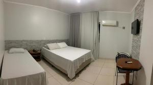 a bedroom with two beds and a table and a television at Marion Pantanal Hotel in Várzea Grande