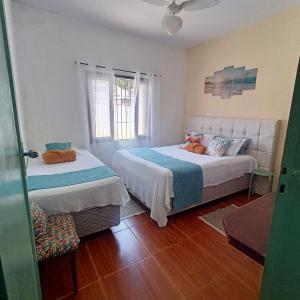 1 Schlafzimmer mit 2 Betten und einem Fenster in der Unterkunft CASA SERENA - Piscina, Wi-fi e Conforto bem pertinho da praia in Itanhaém