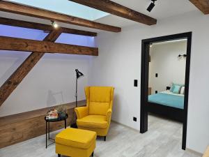 - une chambre avec une chaise jaune et un lit dans l'établissement Ottimo Apartamenty Jagiellońska, à Bydgoszcz