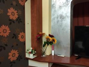 wazon kwiatów na stole obok telewizora w obiekcie My house studio w Bukareszcie