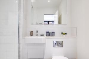 Baño blanco con lavabo y espejo en Contractors Gem, 2 bed, sleeps 6, bathroom & ensuite en Bedford