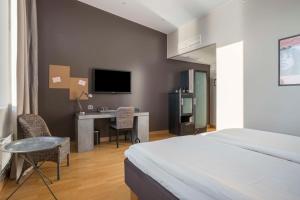 1 dormitorio con 1 cama, escritorio y TV en Aiden by Best Western Stockholm Solna, en Solna