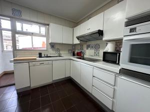 a kitchen with white cabinets and a large window at Oktheway Big Coruña in A Coruña