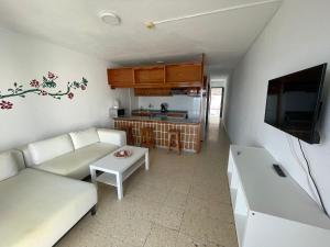 uma sala de estar com um sofá branco e uma televisão em Apartamentos Buenavista em Puerto Rico de Gran Canaria