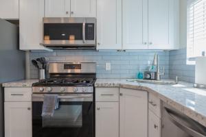 a kitchen with white cabinets and a stove and a microwave at Modern Arcadia Lite Oasis Pool Heater BBQ in Phoenix