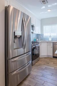 a stainless steel refrigerator in a kitchen with white cabinets at Modern Arcadia Lite Oasis Pool Heater BBQ in Phoenix +33 photos