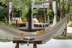 a hammock in a garden with a drink on a table at Chalés Magia do Campeche in Florianópolis