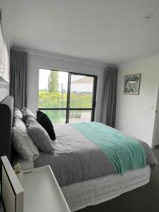 sypialnia z łóżkiem i dużym oknem w obiekcie Hobbiton Countryside Sanctuary w mieście Matamata