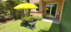 stół i krzesła z żółtym parasolem na trawniku w obiekcie Les Elfes - avec entrée autonome, jardin, parking privé & gourmandises offertes ! - w Tuluzie