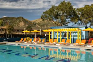 a swimming pool with chairs and umbrellas and a pool at Americana Motor Hotel in Flagstaff