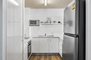 a white kitchen with a refrigerator and a sink at Avalon on Alex Beach 2 Bedroom Apartment in Alexandra Headland