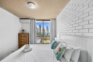 a bedroom with a white brick wall and a bed at Avalon on Alex Beach 2 Bedroom Apartment in Alexandra Headland