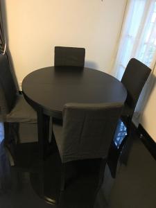 una mesa negra con dos sillas y un ordenador portátil. en Thao, en Serris