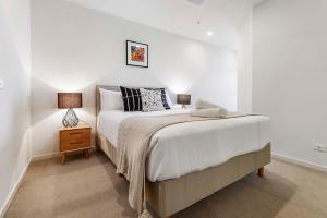 een witte slaapkamer met een bed en een nachtkastje bij Modern Urban Retreat in Brunswick in Melbourne
