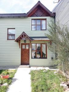 uma casa branca com uma porta castanha e uma entrada em Pirca Ushuaia em Ushuaia