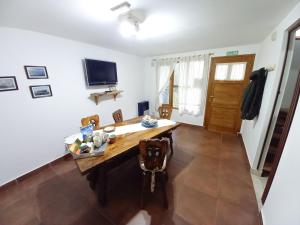 une salle à manger avec une table en bois et une télévision dans l'établissement Pirca Ushuaia, à Ushuaia