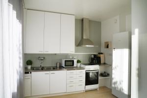 cocina con armarios blancos y nevera blanca en 4-roomIIPerfect locationIICenter, en Oulu