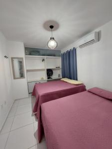 2 Betten in einem Zimmer mit lila Bettwäsche in der Unterkunft Zapipou - Apartamento aconchegante para você aproveitar o melhor de Pipa in Pipa