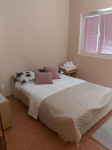 sypialnia z białym łóżkiem z poduszkami i oknem w obiekcie Apartments Ant w Budvie