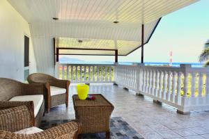a room with a balcony with chairs and a table at Tekauhivai Lodge in Uturoa