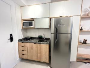 uma cozinha com um frigorífico de aço inoxidável e armários em Studio Minimalista em São Paulo