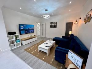 a living room with a blue couch and a tv at Wembley Stadium Luxury 6 bed sleeps 14 in London