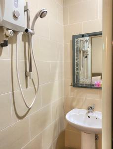 um chuveiro na casa de banho com um lavatório e um espelho em Jasmine Villa em Pantai Cenang