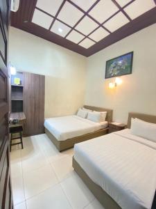 um quarto de hotel com duas camas e um tecto em Jasmine Villa em Pantai Cenang