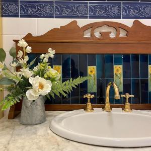 Victoria House Motor Inn في كرويدون: حوض حمام مع إناء من الزهور على منضدة
