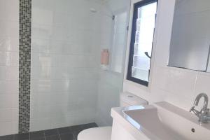 a white bathroom with a toilet and a sink at Ocean High in Yamba +15 photos