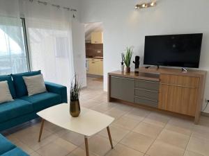 sala de estar con sofá azul y TV de pantalla plana en KANOA LODGE piscine et vue mer en Saint-Claude