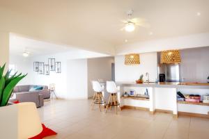 uma cozinha e sala de estar com armários brancos e cadeiras em Oceanfront Penthouse on the beach Bellevue 10 em Kralendijk