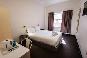 ein kleines Hotelzimmer mit einem Bett und einem Tisch in der Unterkunft YHA Adelaide Central in Adelaide