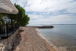 a beach next to the water with a building at Double Room Mandre 3557b in Kolan