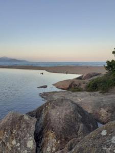 a body of water with some rocks in the water at Residência in Caraguatatuba