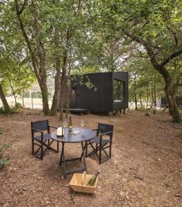 una mesa y sillas en un campo con árboles en A Leira 116 Cabañas de diseño, en Sarria