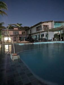 a large swimming pool with a light in front of a building at Slater's House - Casa de praia em frente ao mar in Santa Luzia