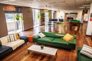a living room with a green couch and a table at YHA Adelaide Central in Adelaide
