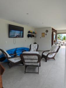 a living room with chairs and a flat screen tv at Slater's House - Casa de praia em frente ao mar in Santa Luzia