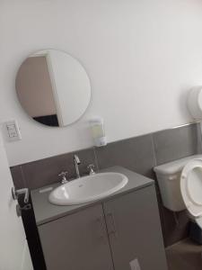 a bathroom with a sink and a mirror and a toilet at Apart272 in Río Cuarto
