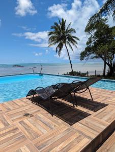a couple of chairs sitting on a wooden deck next to a swimming pool at Slater's House - Casa de praia em frente ao mar in Paripueira